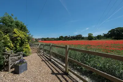 a wooden fence in front of a field of flowers at Little House, Aldringham in Leiston