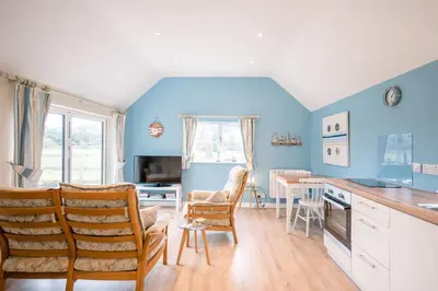 a kitchen with blue walls and a table and chairs at Little House, Aldringham in Leiston