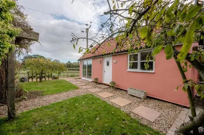 a pink house with a garden in front of it at Little House, Aldringham in Leiston