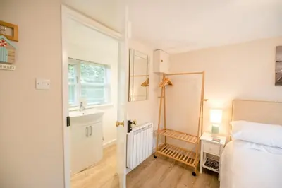 a bedroom with a bed and a sink and a mirror at Little House, Aldringham in Leiston
