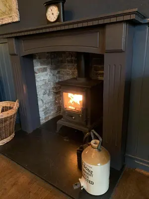 a fireplace with a stove with a fire in it at Three Tuns Ashwell in Ashwell