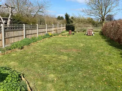 a garden with a fence and a bench in a yard at Honey Cottage in Friston