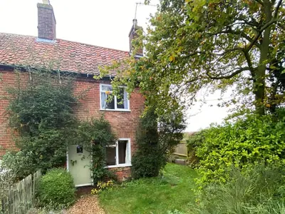 a red brick house with a white door at Honey Cottage in Friston
