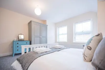 a bedroom with a white bed and a blue dresser at 2 Abbey Mews, Leiston in Leiston
