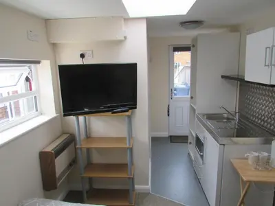 a small kitchen with a flat screen tv on the wall at Independent two bed en-suite annex, close to city in Cambridge
