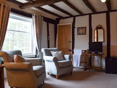 a living room with two chairs and a tv at The Old Bakery in Pulham Saint Mary Magdalene