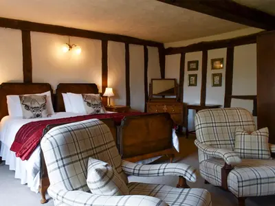 a bedroom with a bed and two chairs at The Old Bakery in Pulham Saint Mary Magdalene