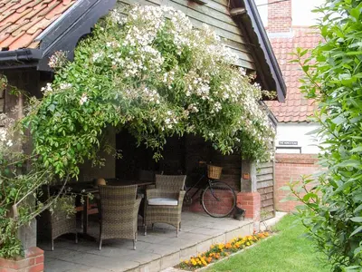 a patio with a table and chairs under a tree at The Old Bakery in Pulham Saint Mary Magdalene