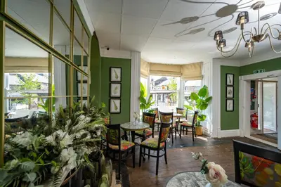 a restaurant with green walls and tables and chairs at The Bramley House Hotel in Chatteris