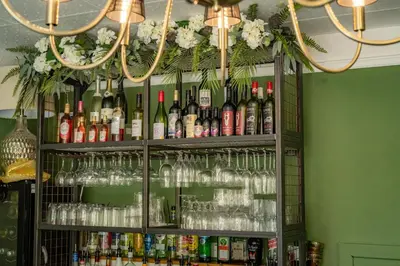 a shelf filled with glasses and bottles of alcohol at The Bramley House Hotel in Chatteris
