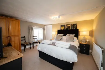 a bedroom with a large bed with white sheets and pillows at The Bramley House Hotel in Chatteris