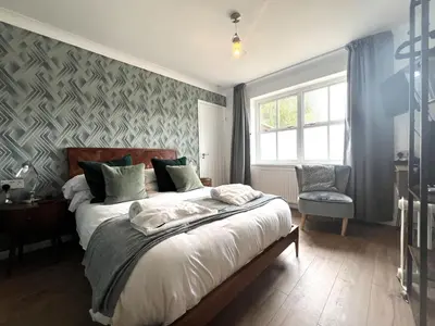 a bedroom with a bed and a chair and a window at The Bramley House Hotel in Chatteris