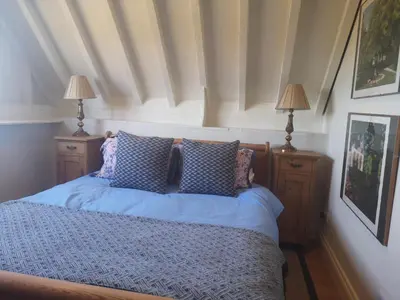 a bedroom with a bed with blue sheets and two lamps at The Queen's Head in Hawkedon