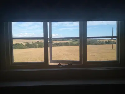 a window with a view of a field behind it at The Queen's Head in Hawkedon