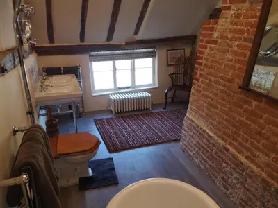 a bathroom with a toilet and a sink and a brick wall at The Queen's Head in Hawkedon