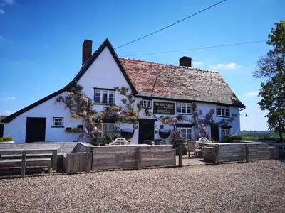 a white building with a fence in front of it at The Queen's Head in Hawkedon