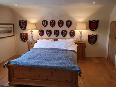 a bedroom with a bed and a bunch of hats on the wall at The Queen's Head in Hawkedon