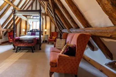 a attic room with two chairs and a bed at Doves Barn in Needham Market