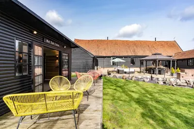 a patio with yellow chairs and a yard at Doves Barn in Needham Market