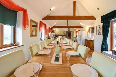 a long dining room with a long table and chairs at Doves Barn in Needham Market