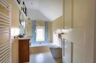 a bathroom with a sink and a toilet and a window at Finest Retreats - The Stables at Crimplesham in Stradsett