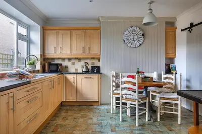 a kitchen with a table and a clock on the wall at Finest Retreats - The Stables at Crimplesham in Stradsett