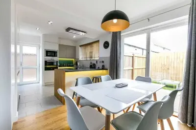a kitchen and dining room with a white table and chairs at Spacious Modern Garden Family Home in Cambridge