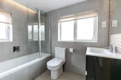 a bathroom with a toilet and a tub and a sink at Spacious Modern Garden Family Home in Cambridge