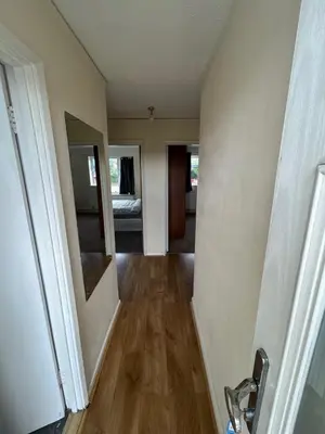 an empty room with a hallway with wooden floors at 3 Bedroom Thundersley Apartment in Rayleigh