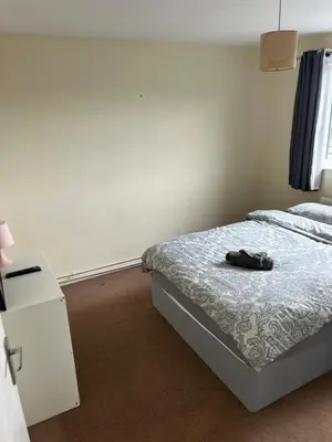a bedroom with a bed and a dresser with a shoe on it at 3 Bedroom Thundersley Apartment in Rayleigh