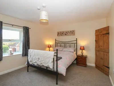 a bedroom with a bed and a dresser and a window at Rose Cottage in Stoke Ferry