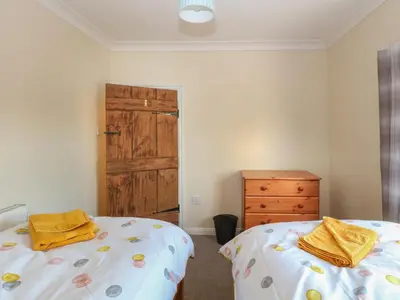 a bedroom with two beds and a wooden door at Rose Cottage in Stoke Ferry
