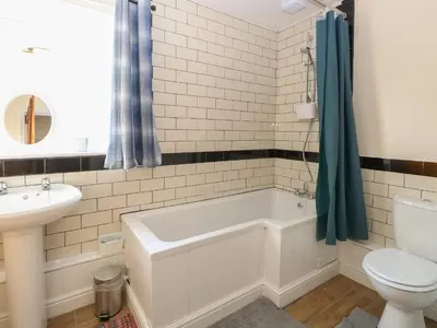 a bathroom with a tub and a toilet and a sink at Rose Cottage in Stoke Ferry