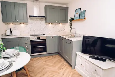 a kitchen with green cabinets and a table and a tv at Caroline Court - 1 Bedroom Apartment in Colchester