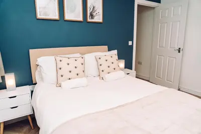 a bedroom with a white bed and a blue wall at Caroline Court - 1 Bedroom Apartment in Colchester