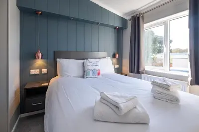 a bedroom with a large white bed with towels on it at Savannah Lodge - Aldeburgh Coastal Cottages in Sizewell