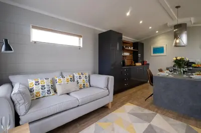 a living room with a couch and a kitchen at Savannah Lodge - Aldeburgh Coastal Cottages in Sizewell