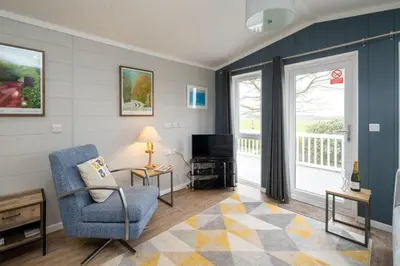 a living room with a chair and a television at Savannah Lodge - Aldeburgh Coastal Cottages in Sizewell
