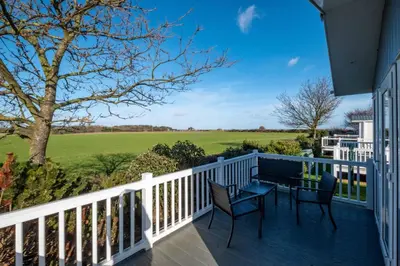 a balcony with a table and chairs and a view of a field at Savannah Lodge - Aldeburgh Coastal Cottages in Sizewell
