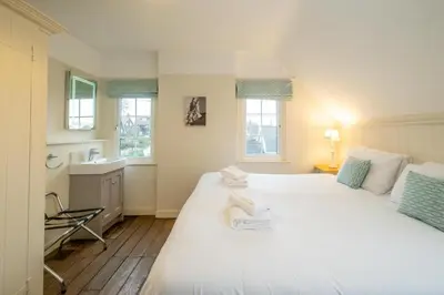 a bedroom with a large white bed and windows at Sanctuary House in Thorpeness