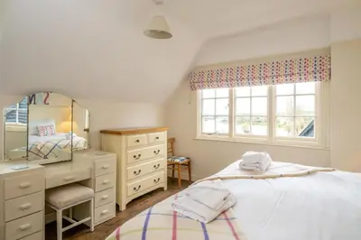a bedroom with a bed and a dresser and a window at Sanctuary House in Thorpeness
