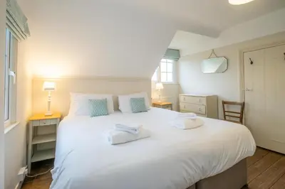 a bedroom with a large white bed with two towels on it at Sanctuary House in Thorpeness