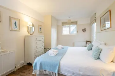 a bedroom with a large white bed with a blue blanket at Sanctuary House in Thorpeness