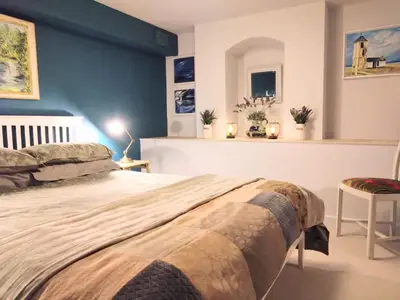 a bedroom with a large bed with a blue wall at Beachfront Studio Apartment in Felixstowe