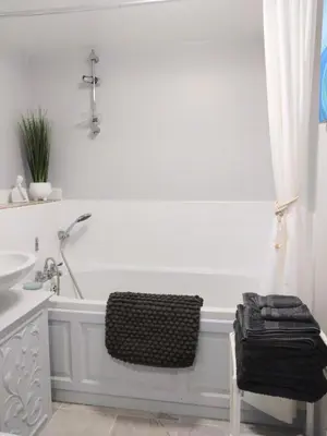 a white bathroom with a tub and a sink at Beachfront Studio Apartment in Felixstowe