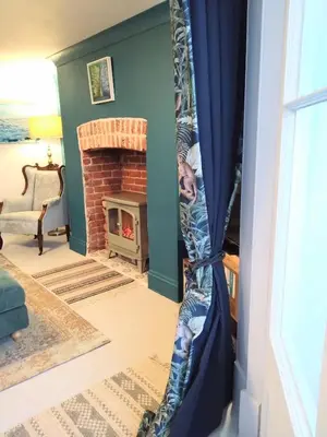 a fireplace in a living room with blue curtains at Beachfront Studio Apartment in Felixstowe