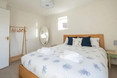 a bedroom with a large bed with blue and white sheets at April Cottage, Aldeburgh - Close to Aldeburgh beach and High Street - Managed by Aldeburgh Coastal Cottages in Aldeburgh