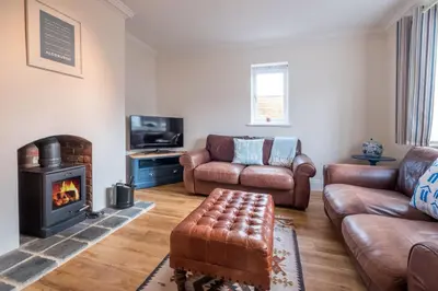 a living room with leather furniture and a fireplace at April Cottage, Aldeburgh - Close to Aldeburgh beach and High Street - Managed by Aldeburgh Coastal Cottages in Aldeburgh