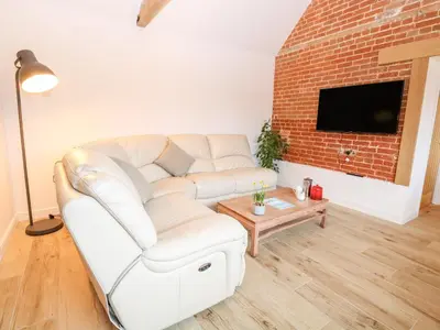 a living room with a white couch and a brick wall at The Duck House in Thetford