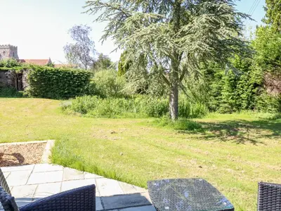 a patio with chairs and a tree in a yard at The Duck House in Thetford